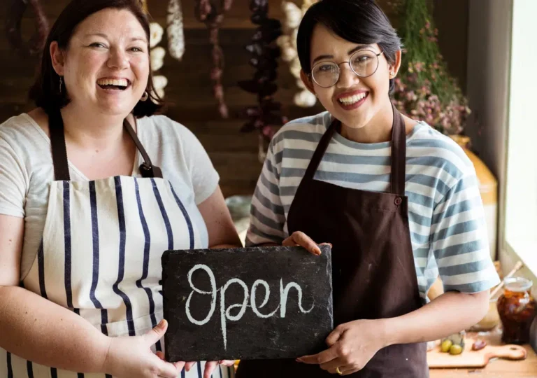 Shop owners holding an open sign